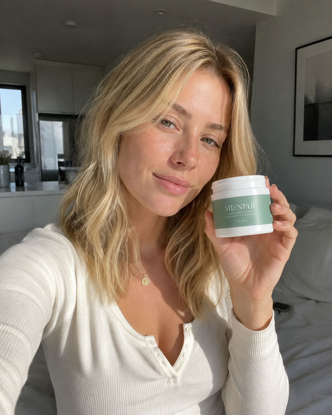 Blonde woman in a white henley holding the Menphi jar in a sunlit bedroom